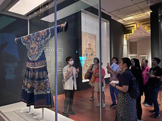Women group visit a museum together with a tour guide explaining the history and elements of the Chinese traditional clothing