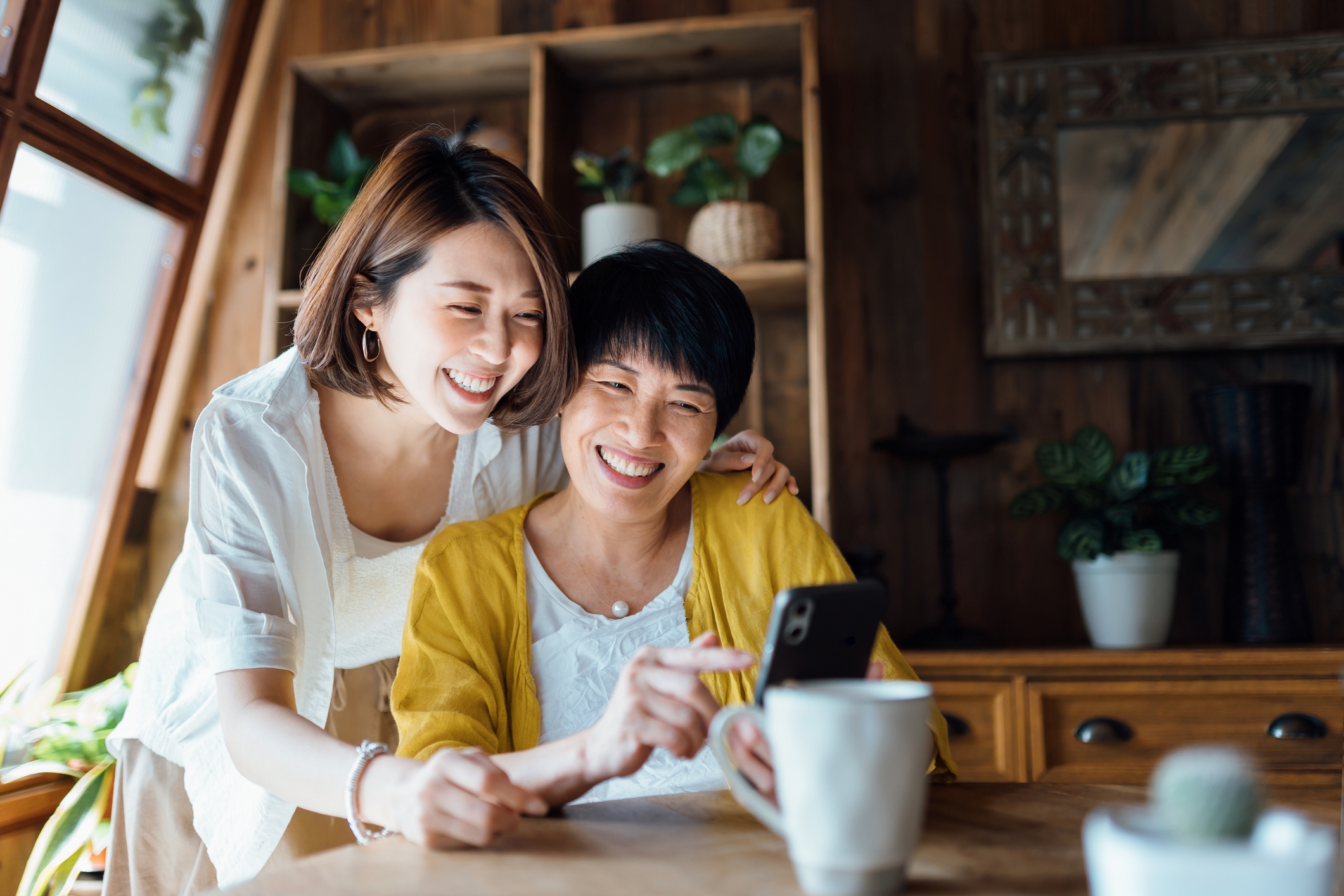 Two women indoor watching a phone with smile