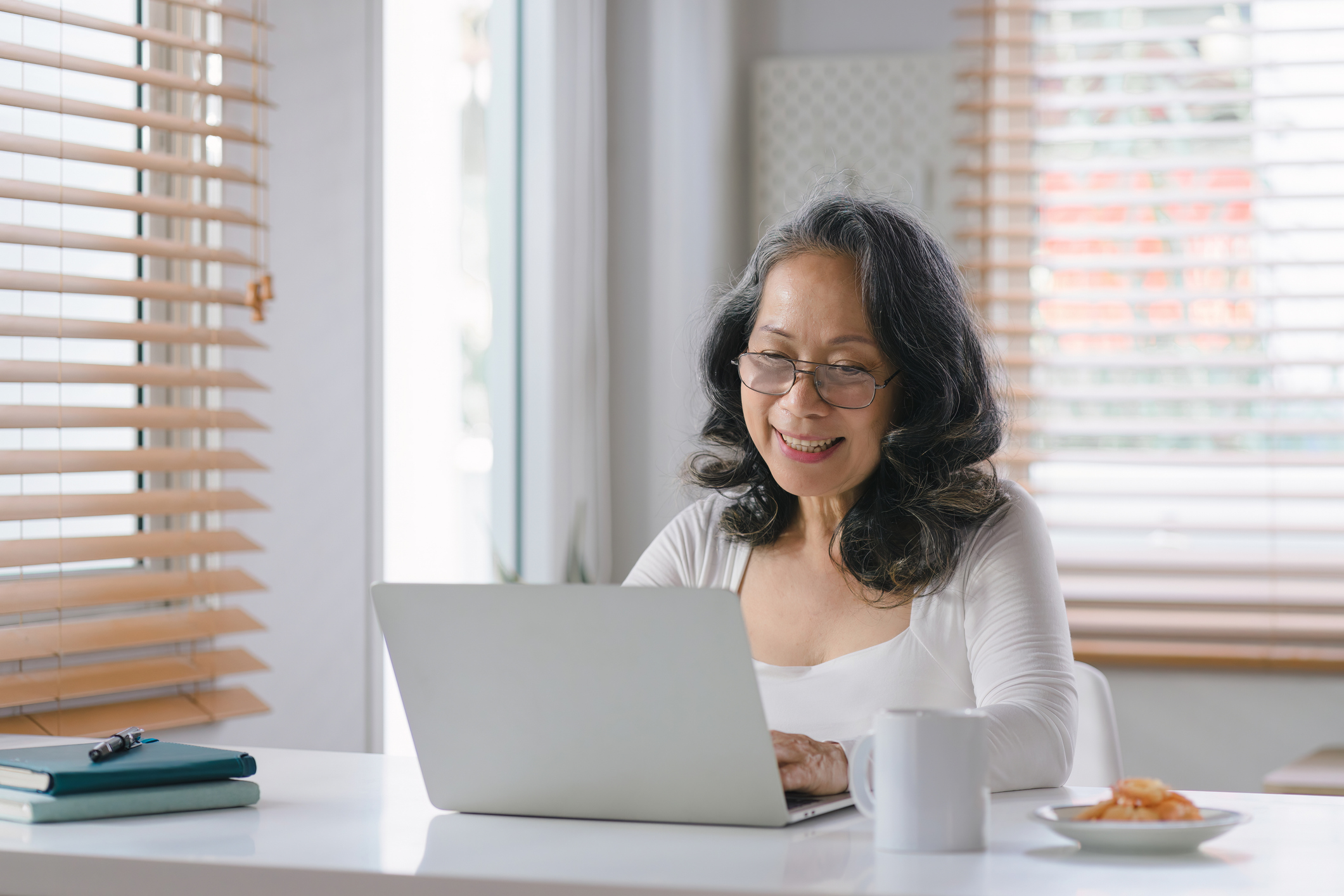 Elder woman with glasses indoor using a laptop