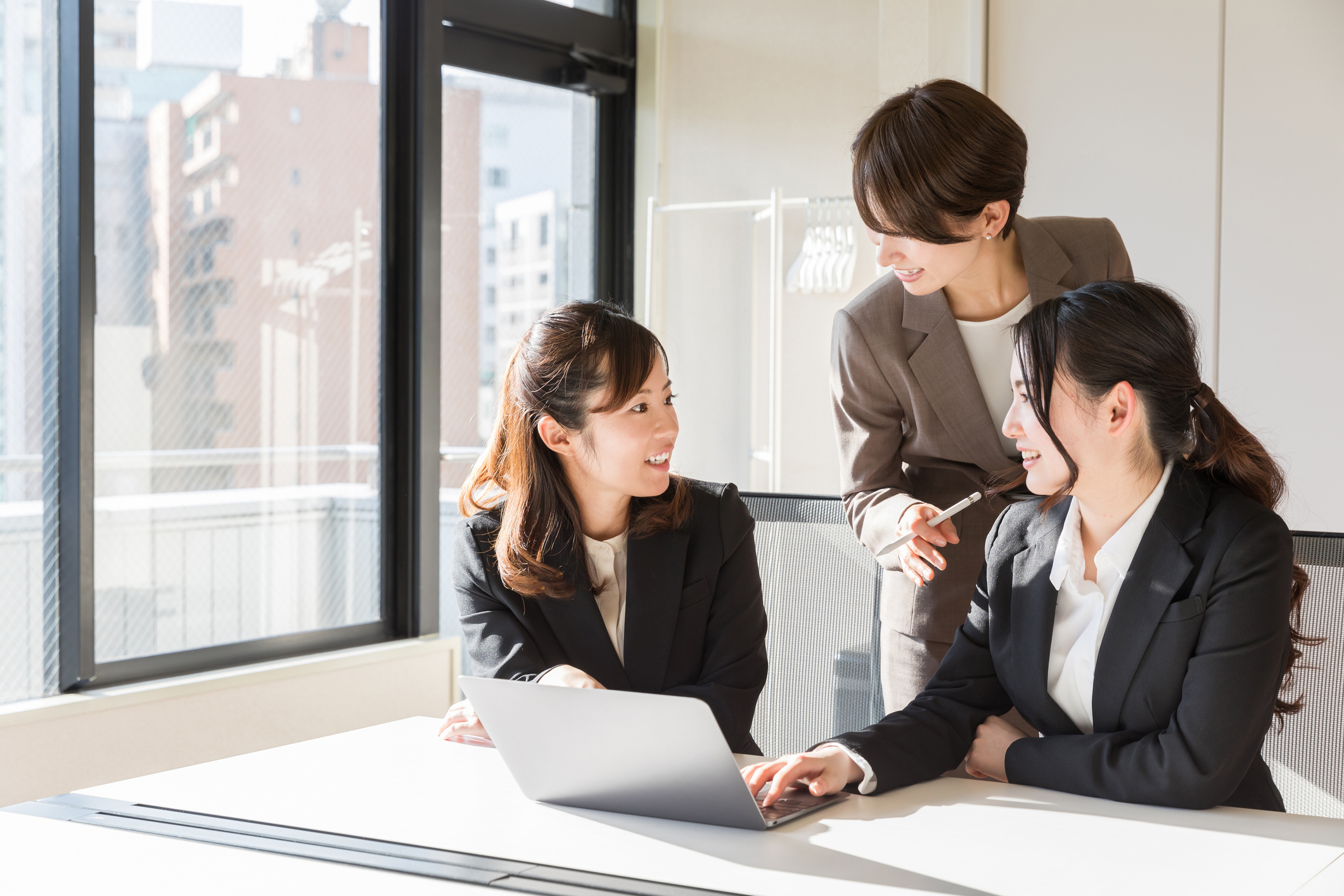 Three women in suit discussing in an office