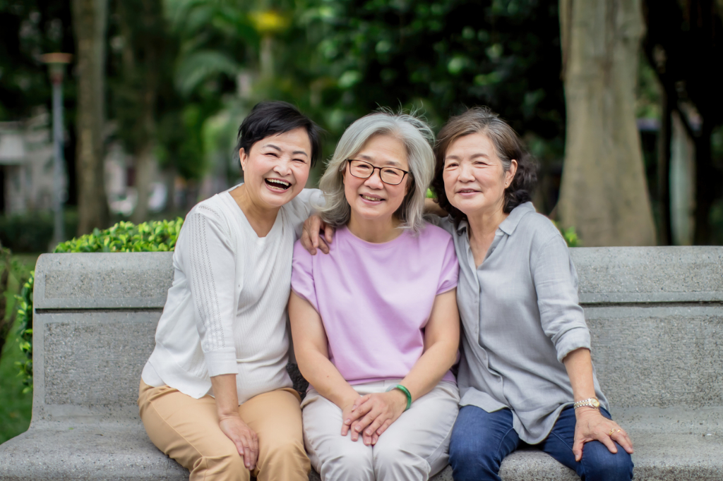 group of happy elderly lady sitting on a park bench